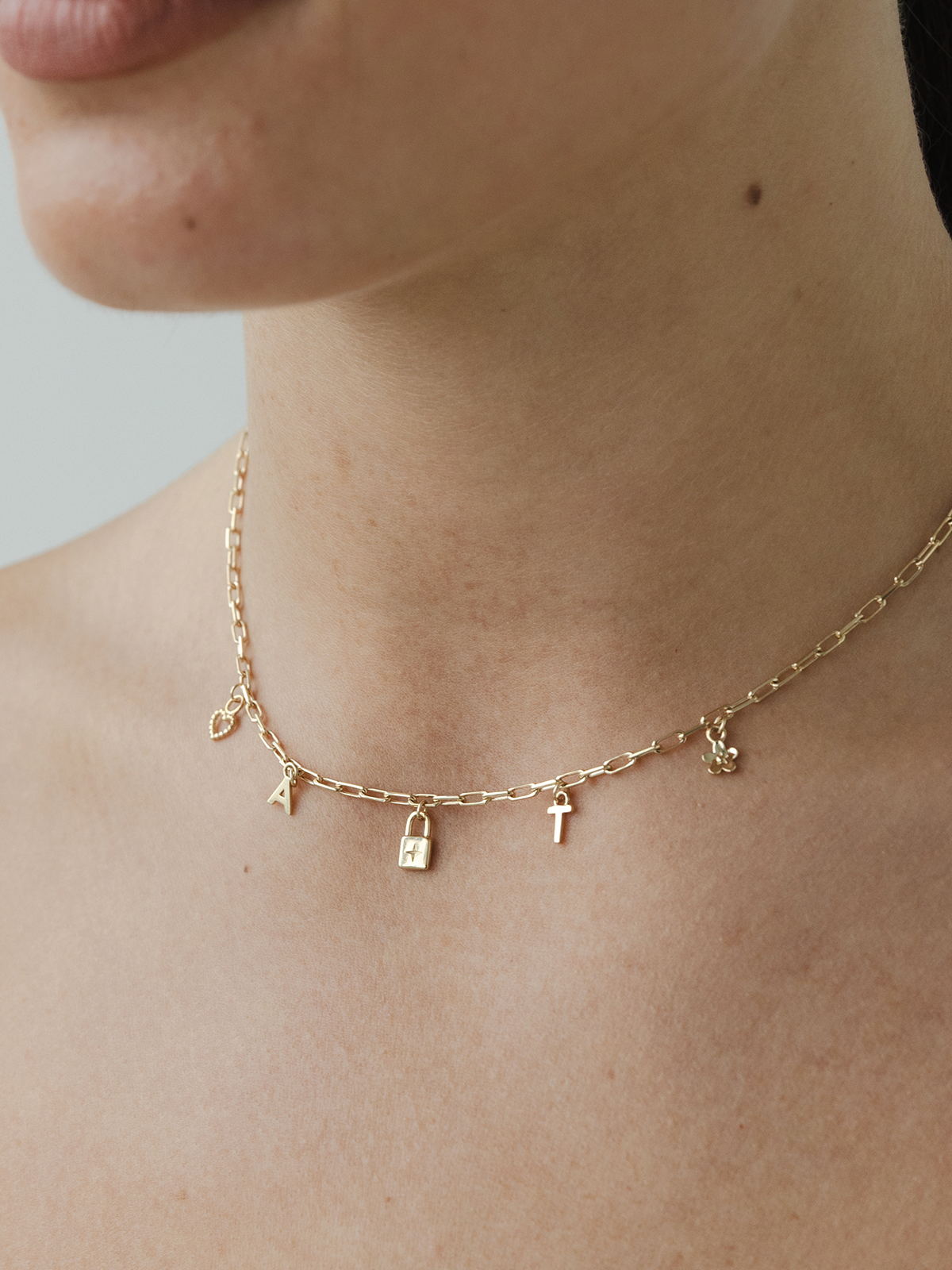Solid old choose your charms necklace on a person's neck against a neutral background