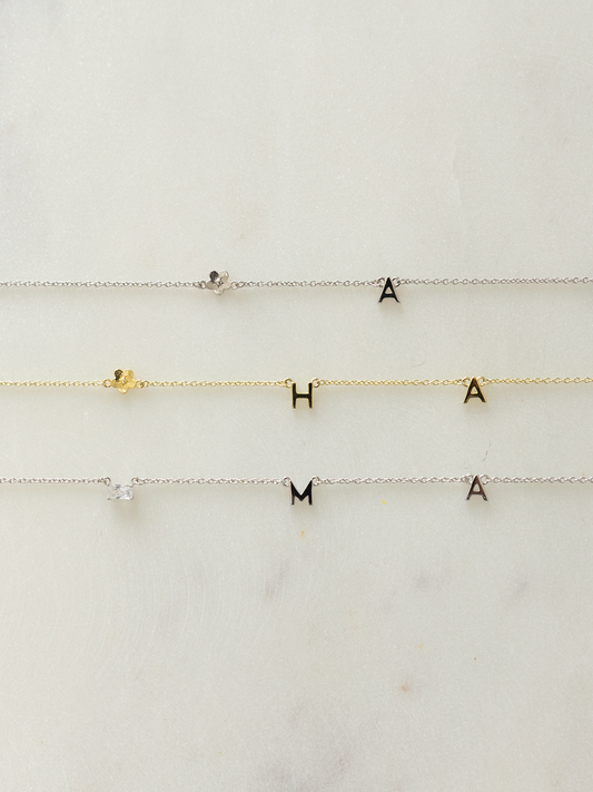 Three choose your letters jewellery in silver & gold with letter and pendant charms on a white background