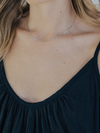 Close-up of a person wearing a delicate silver necklace with a blurred background