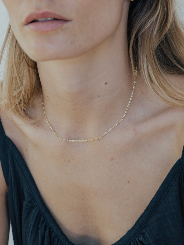 Close-up of a person wearing a delicate gold necklace.