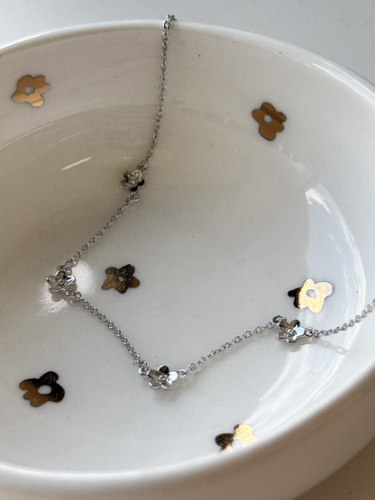 Silver necklace with flower pendants on a white dish