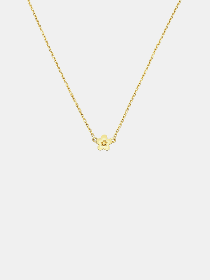 Solid gold necklace with a small daisy day flower pendant on a light grey background