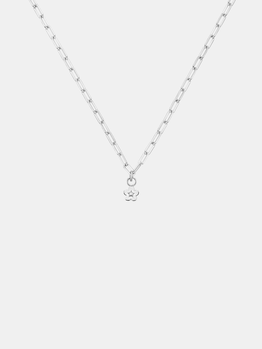 Gold necklace with a daisy day flower pendant on a light gray background