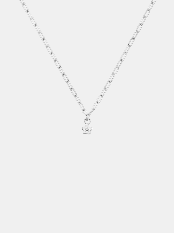 Gold necklace with a daisy day flower pendant on a light gray background