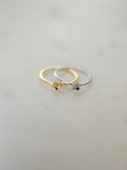 Two gold and silver rings with daisy pendants on a light gray background