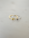 Two gold and silver rings with daisy pendants on a light gray background