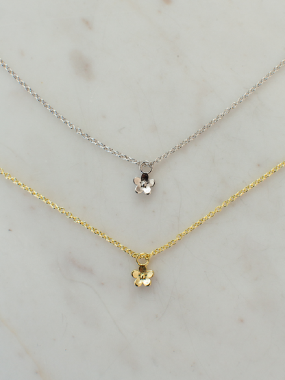 Two necklaces, one gold and one silver, on a light marble background