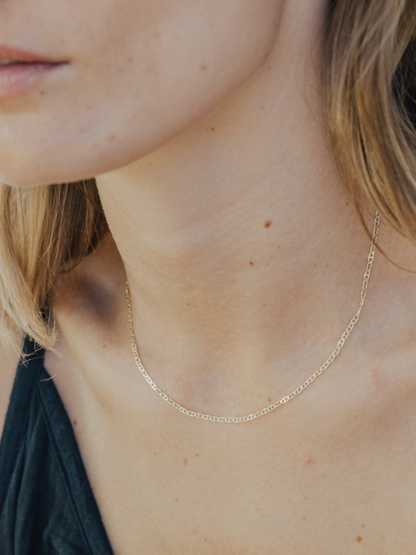 Close-up of a person wearing a gold necklace with a blurred background