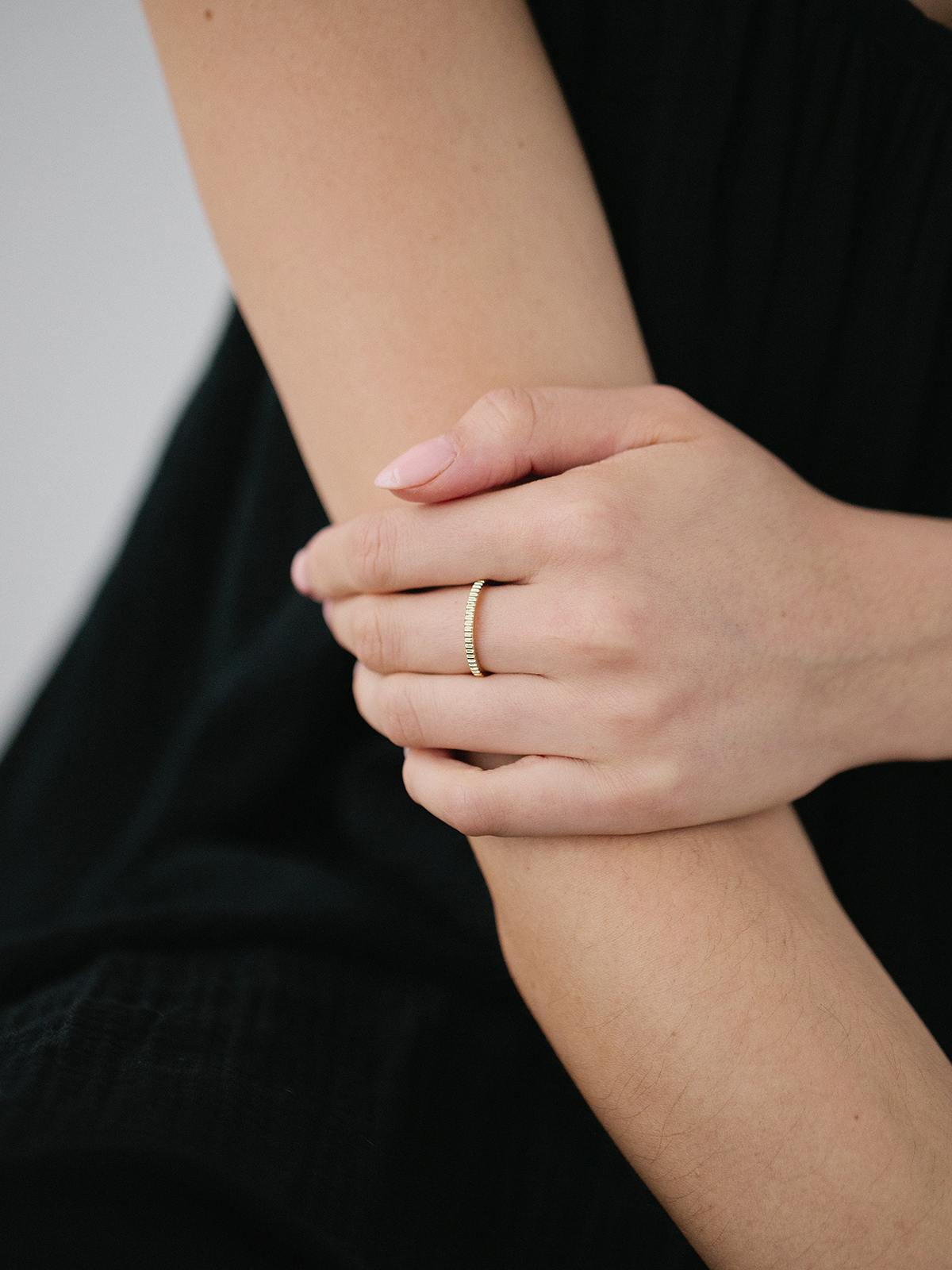 Close-up of a hand wearing a gold ring on a black background