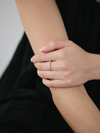 Close-up of a hand wearing a gold ring on a black background