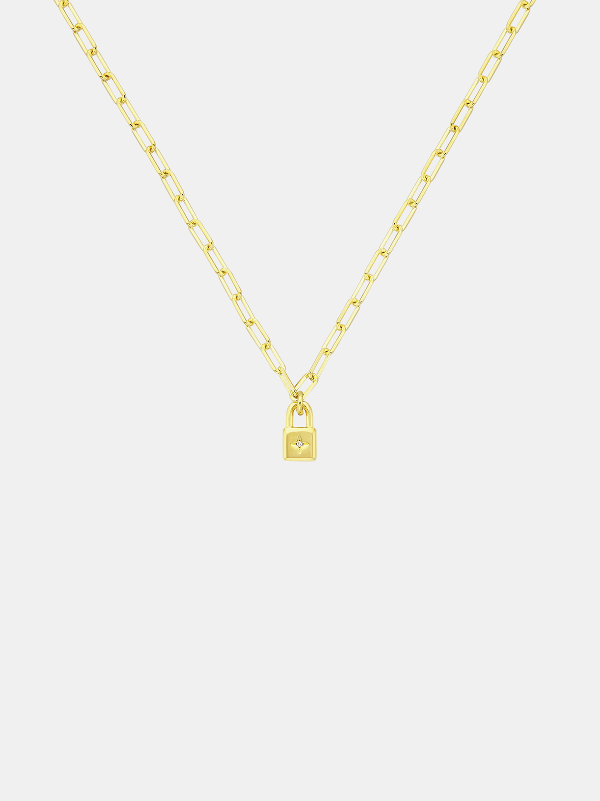 Gold necklace with a lock-shaped pendant on a light gray background