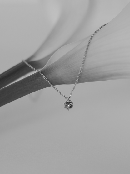 Silver necklace with a lily pendant on a light grey background