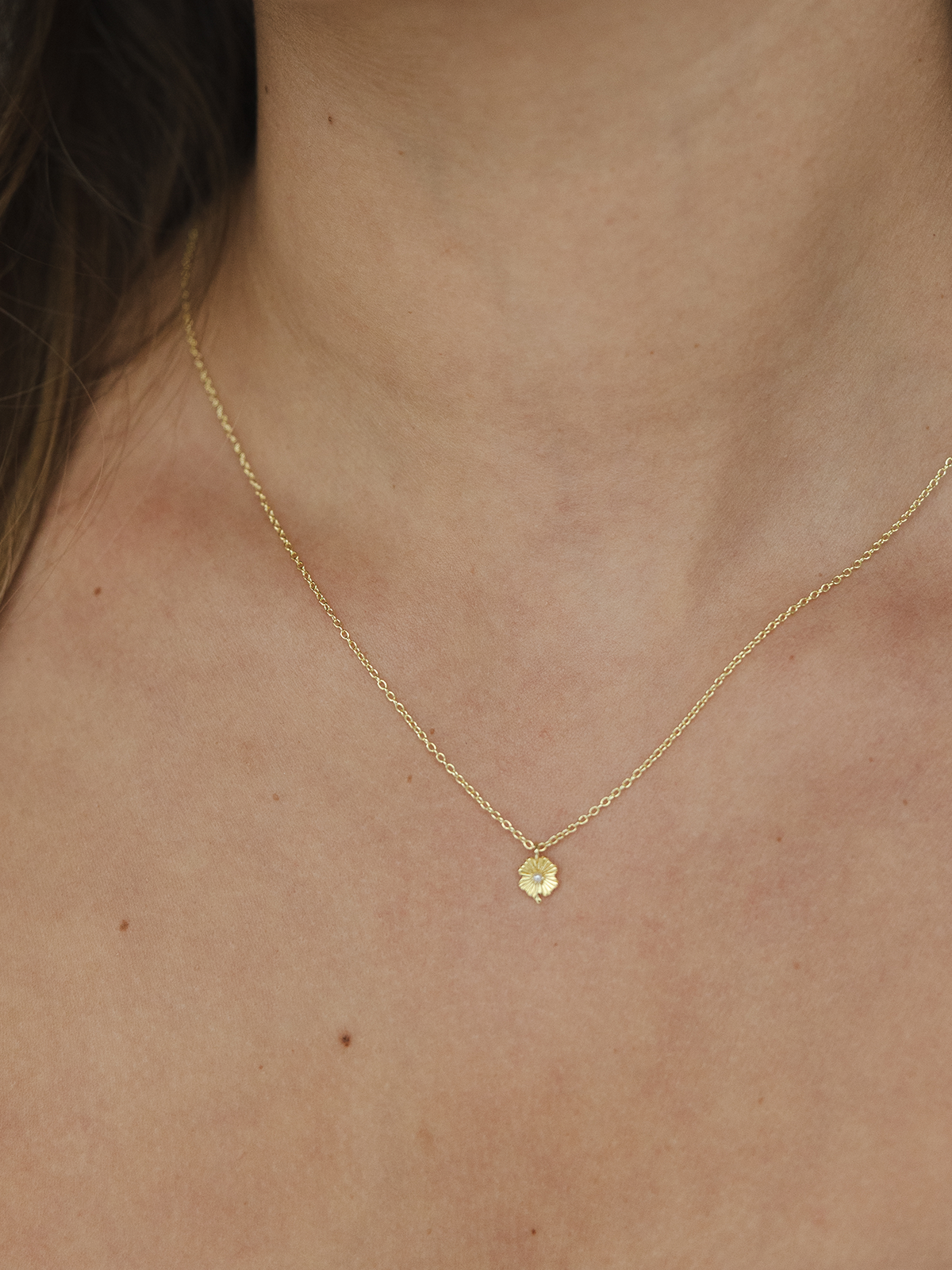 Gold necklace with a small pendant on a person's neck