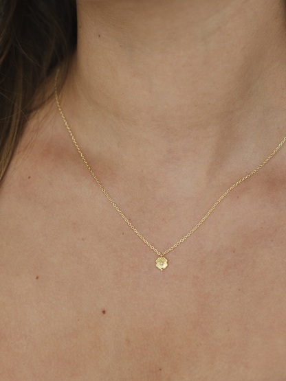Gold necklace with a small pendant on a person's neck