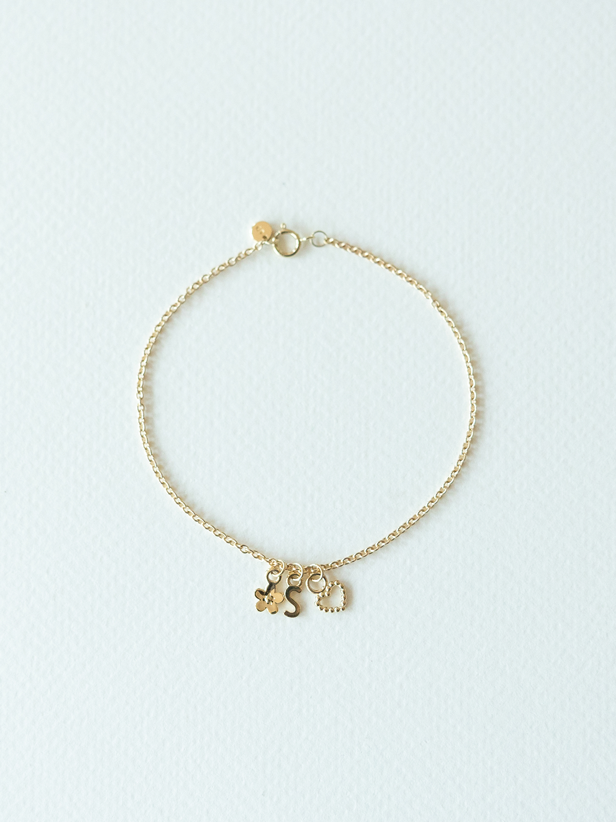 Mix It Up solid gold charm bracelet on a cable chain on a light blue background