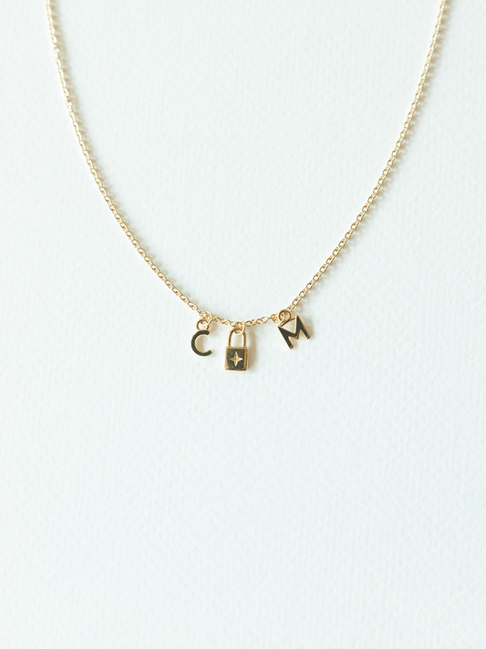 Solid gold mix it up necklace on cable chain with three small pendants on a white background
