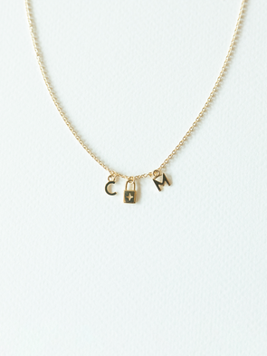 Solid gold mix it up necklace on cable chain with three small pendants on a white background