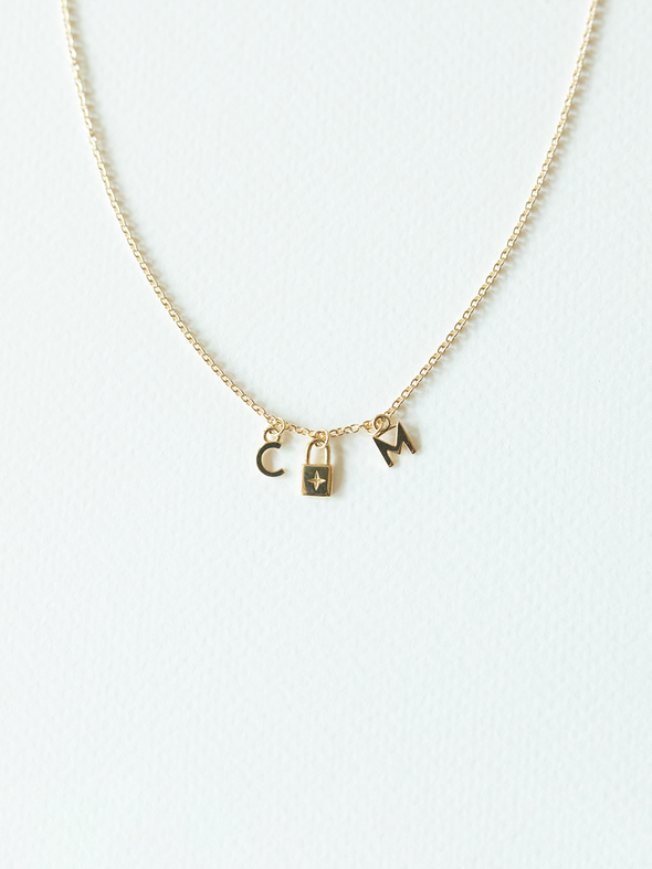 Solid gold mix it up necklace on cable chain with three small pendants on a white background