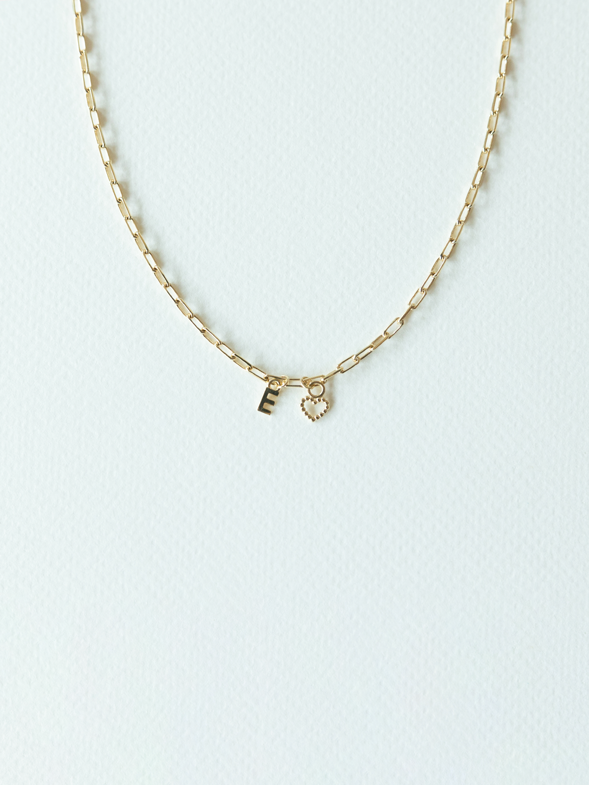 Solid gold mix it up necklace on mini links chain with two small pendants on a white background