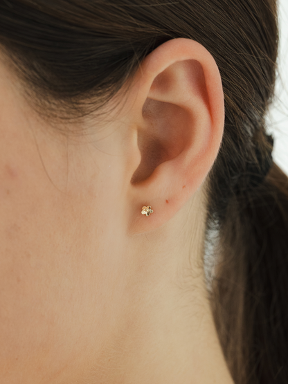 Close-up of an ear with a solid gold daisy day stud earring
