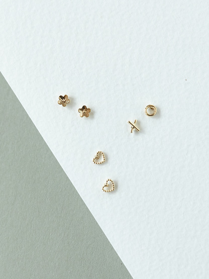 Set of micro solid gold earrings on a light grey background