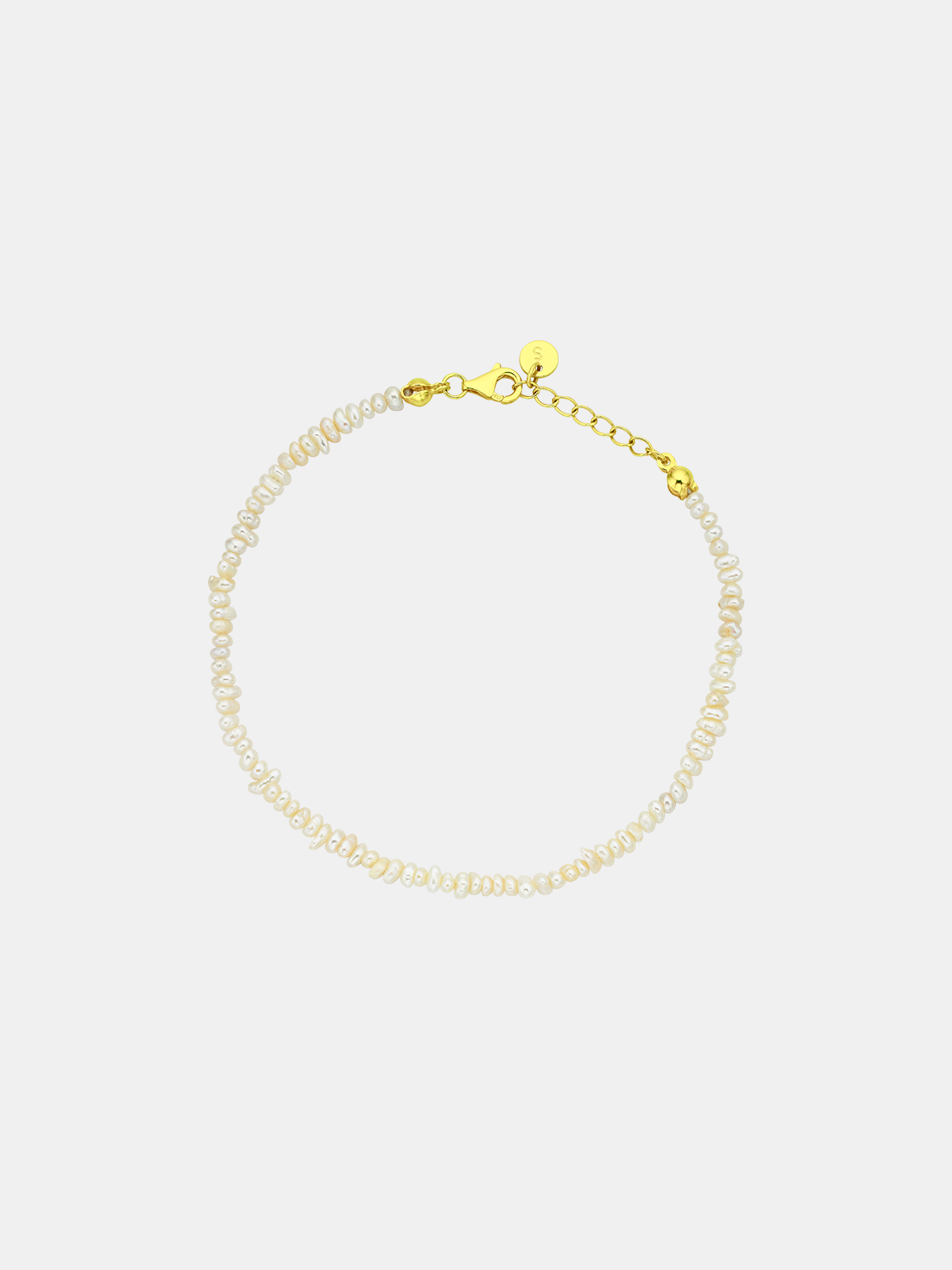 Pearl bracelet with gold clasp on a light gray background