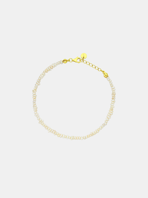 Pearl bracelet with gold clasp on a light gray background