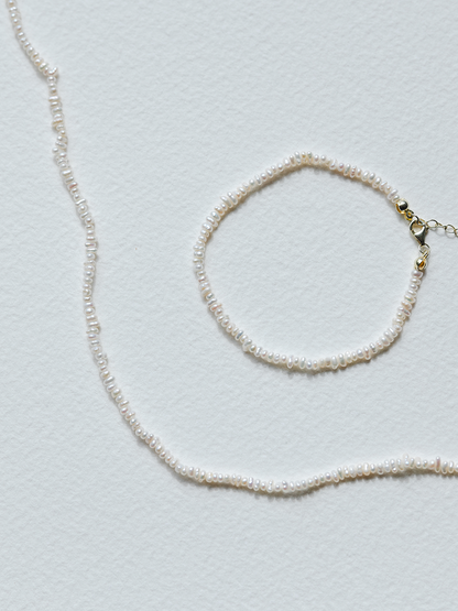 Pearl necklace and bracelet on a light gray background