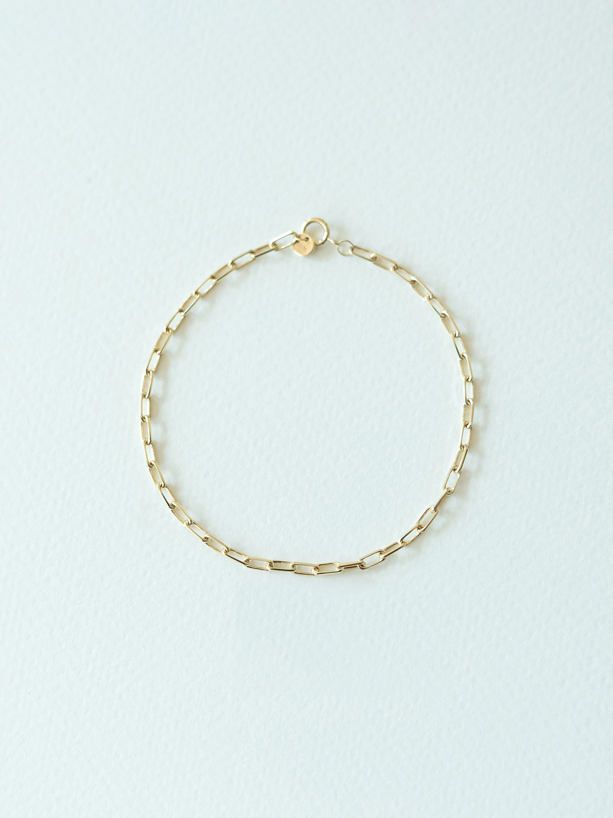 Gold chain bracelet on a light blue background