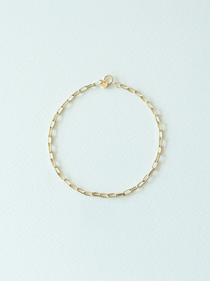 Gold chain bracelet on a light blue background