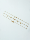 Three solid gold mix it up bracelets with various charms on a light gray background 