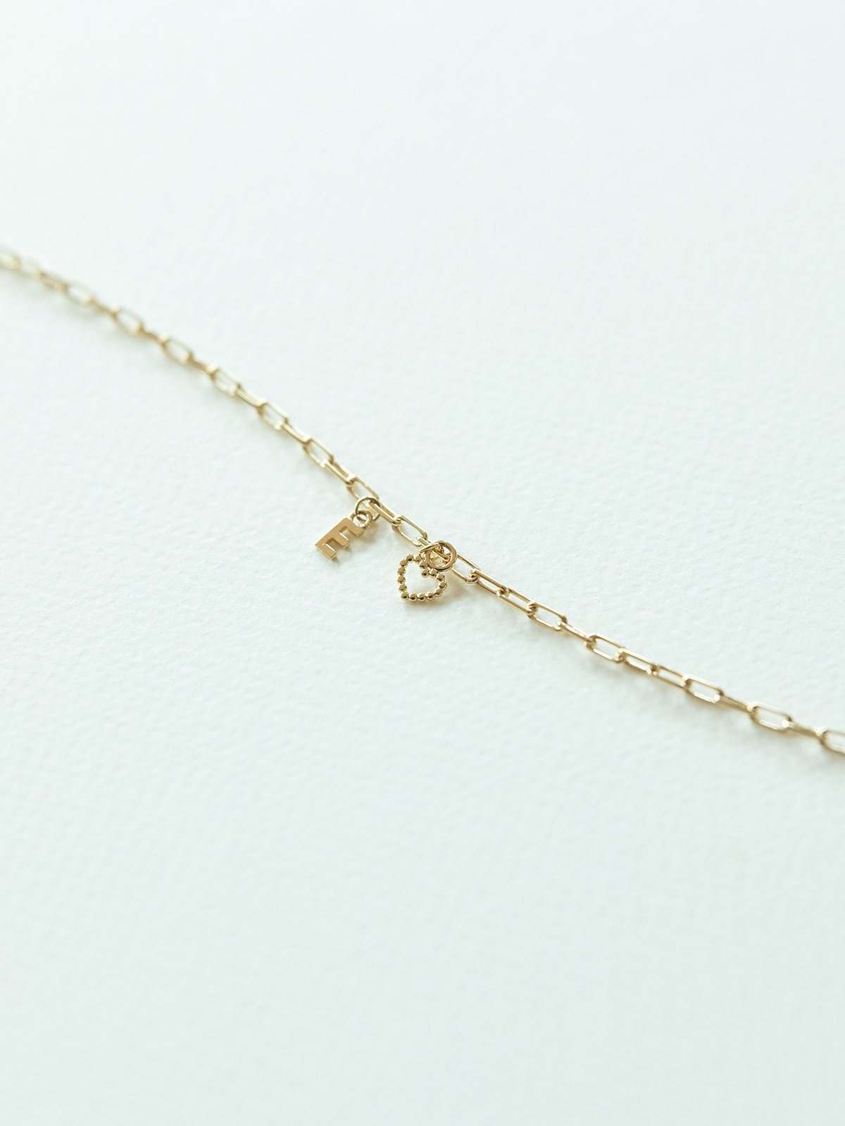 Solid gold mix it up charm jewellery with a dotty love heart charm & little letter on a light gray background