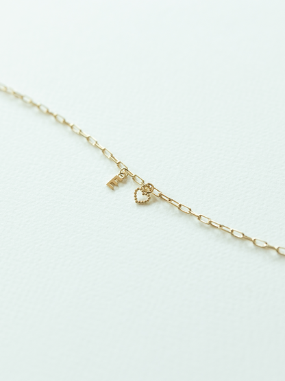 Solid gold mix it up charm jewellery with a dotty love heart charm & little letter on a light gray background