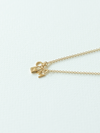 Solid gold mix it up necklace on cable chain with three small pendants on a white background