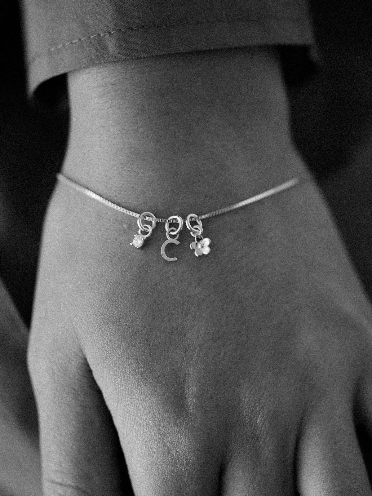 Silver Mix It Up bracelet with charms on a person's wrist against a dark background