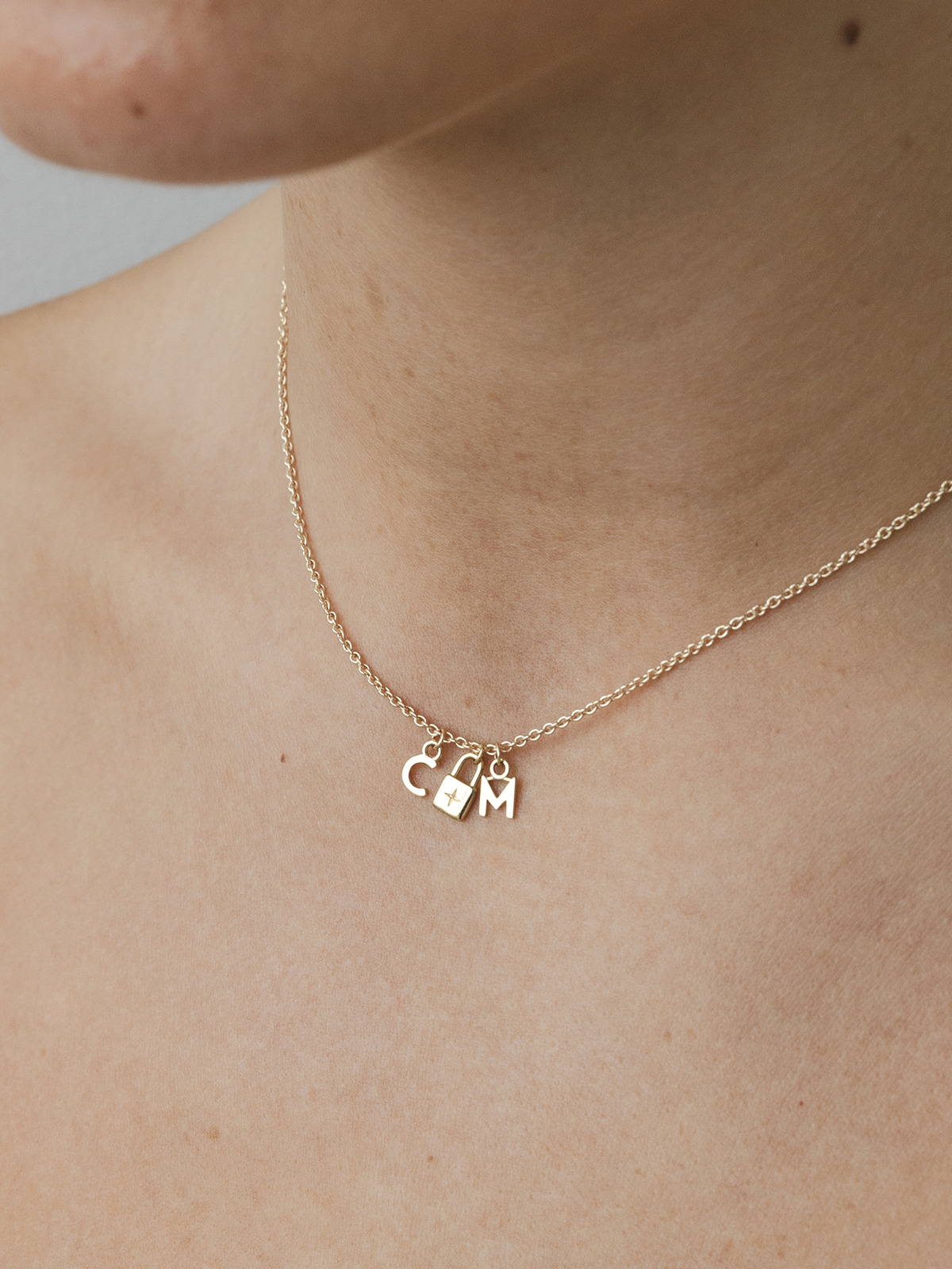 Gold necklace with charms on a person's neck against a neutral background