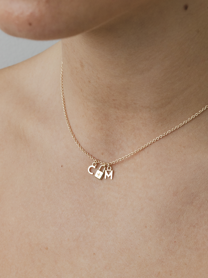 Gold necklace with charms on a person's neck against a neutral background