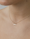 Gold necklace with charms on a person's neck against a neutral background