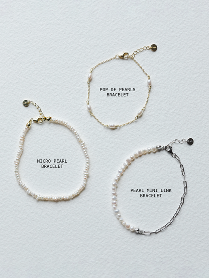 Three pearl bracelets with labels on a light gray background