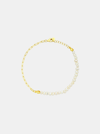Gold bracelet with pearl accents on a light gray background