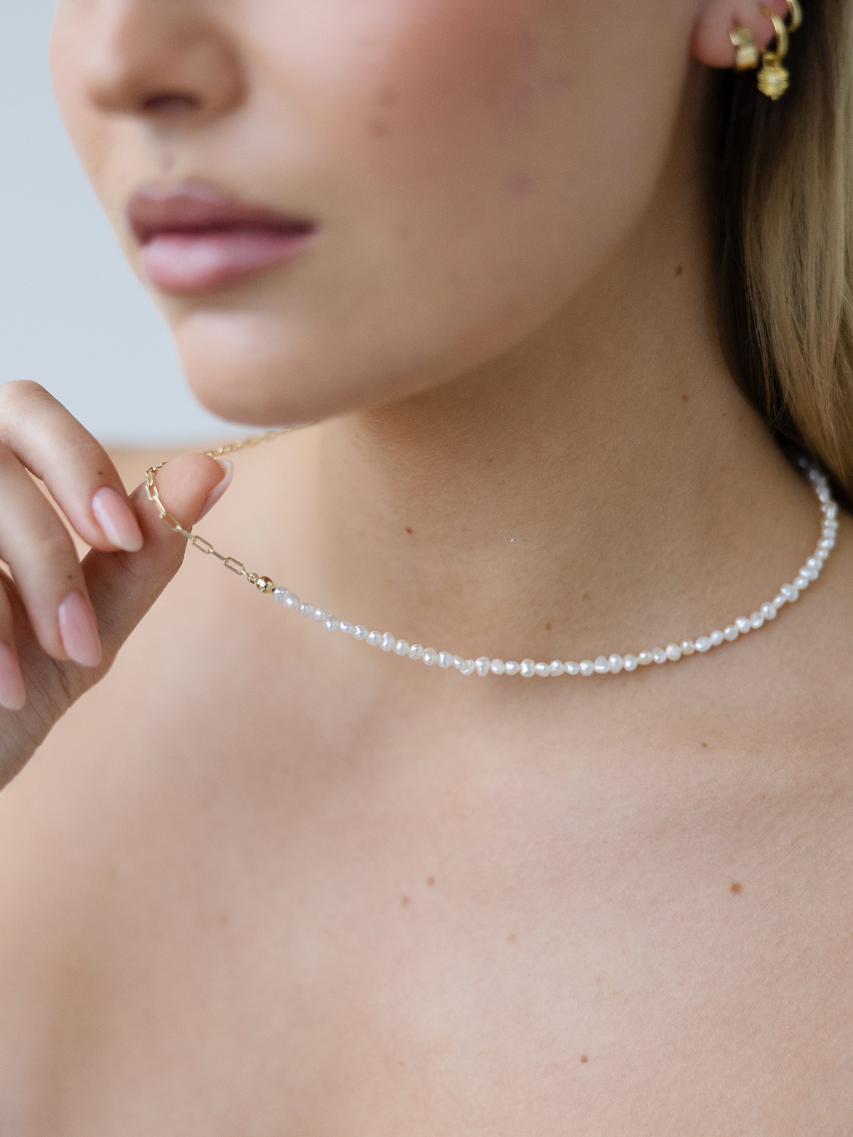 Close-up of a pearl necklace worn by a person with a neutral background