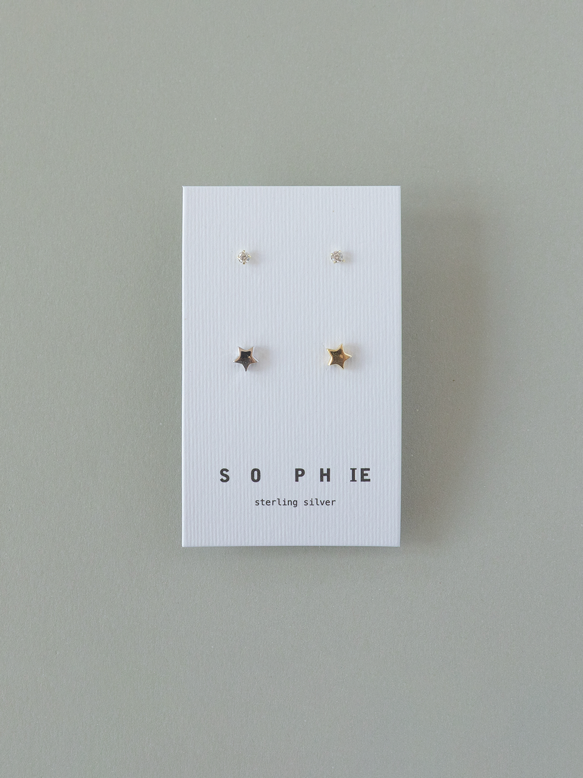 Set of star-shaped earrings on a 'Sophie' branded card against a gray background