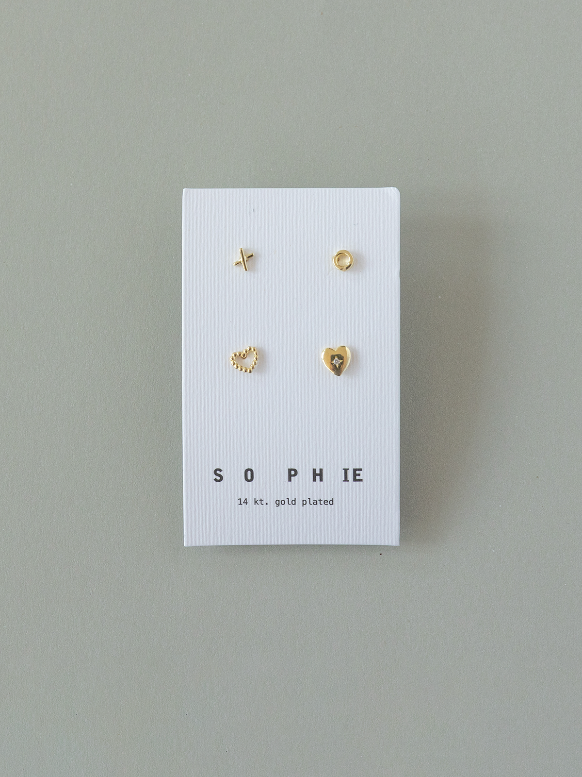 Set of gold earrings on a 'SOPHIE' branded card against a gray background