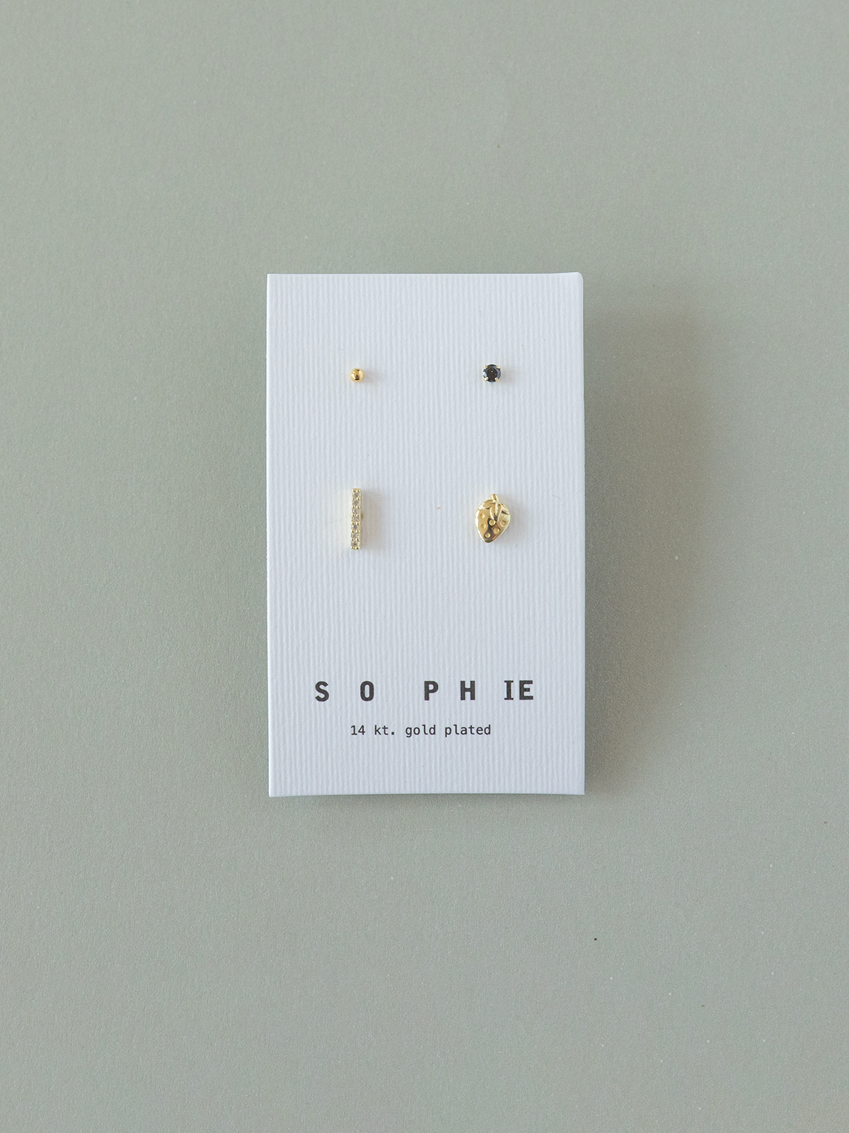 Set of gold earrings on a 'Sophie' branded card against a gray background