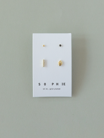 Set of gold earrings on a 'Sophie' branded card against a gray background
