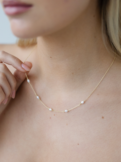 Gold necklace with small pearls on a person's neck