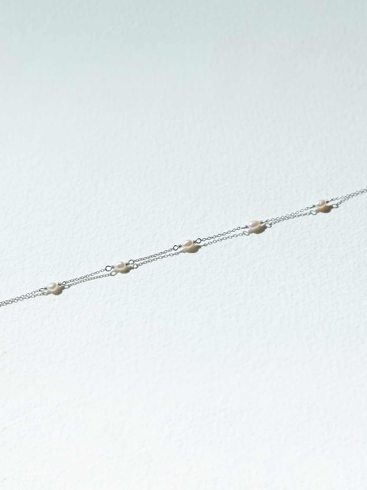 Delicate silver chain bracelet on a light gray background