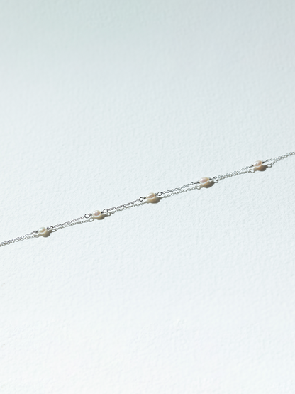 Delicate silver chain bracelet on a light gray background