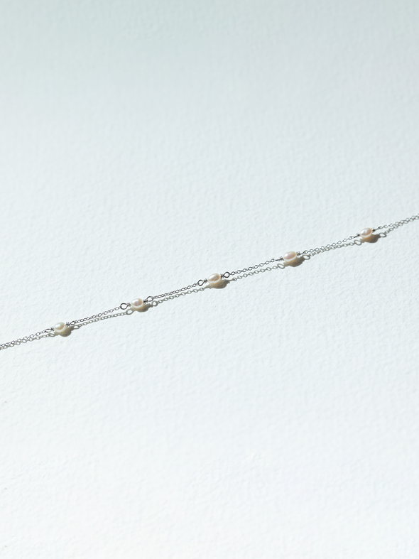 Delicate silver chain bracelet on a light gray background
