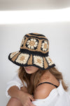 Woman wearing a crocheted sun hat with a geometric pattern on a white background